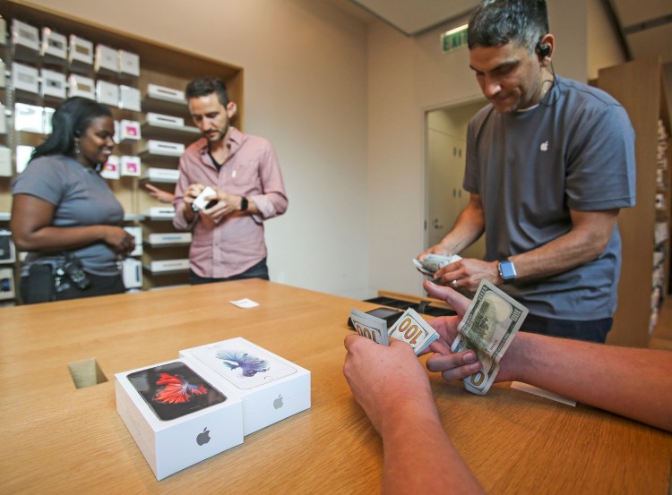 A customer pays with cash for his Apple iPhone 6s and iPhone 6s Plus smartphones at an Apple store in Los Angeles. The Associated Press