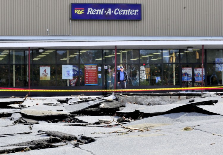 Rent -A- Center employee Merle Gordon looks over the large sections of buckled pavement in the parking lot at a mini-mall in Skowhegan on Thursday. During the storm on Wednesday the truck Gordon usually drives sank in a hole as the water flooded the lot. “I’m lucky it was my day off yesterday,” Gordon said.