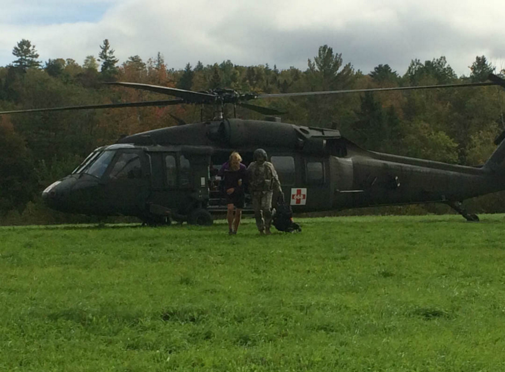 Appalachian Trail thru-hiker Gabrielle Grace is assisted away from a Maine Army National Guard Blackhawk helicopter by a crew member. Grace, 26, of Baltimore, Maryland, and two other women were cut off by the flooding East Branch of the Piscataquis River Thursday.