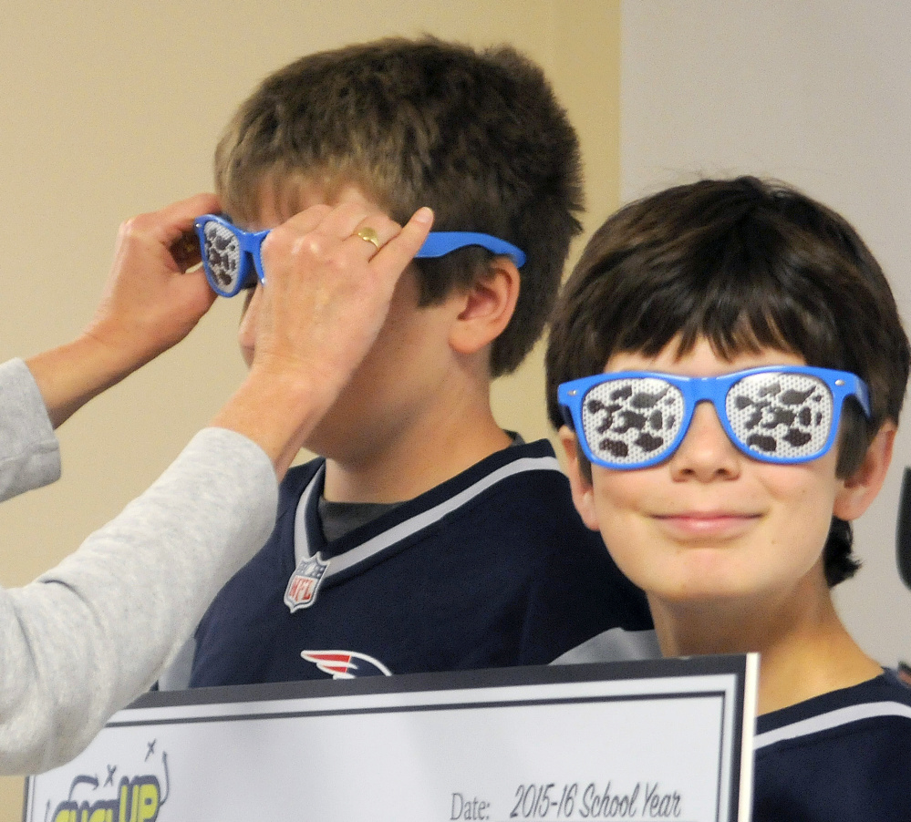 Katie Hoffman of the Maine Dairy and Nutrition Council places sunglasses on Pittston Consolidated School students Casey Paul, left, and Tommy Murphy on Thursday when the school received a check for $1,400 from the state council.