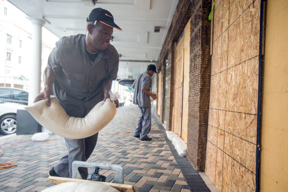 Perry Williams, 47, left, and Alaric Nixon, 28, place sandbags on the storefront of Diamond's International store, in preparation for the arrival of hurricane Joaquin in Nassau, Bahamas, Thursday, Oct. 1, 2015. Joaquin unleashed heavy flooding as it roared through sparsely populated islands in the eastern Bahamas as a Category 4 storm, with forecasters warning it could grow even stronger before carving a path that would take it near the U.S. East Coast. (AP Photo/Tim Aylen)