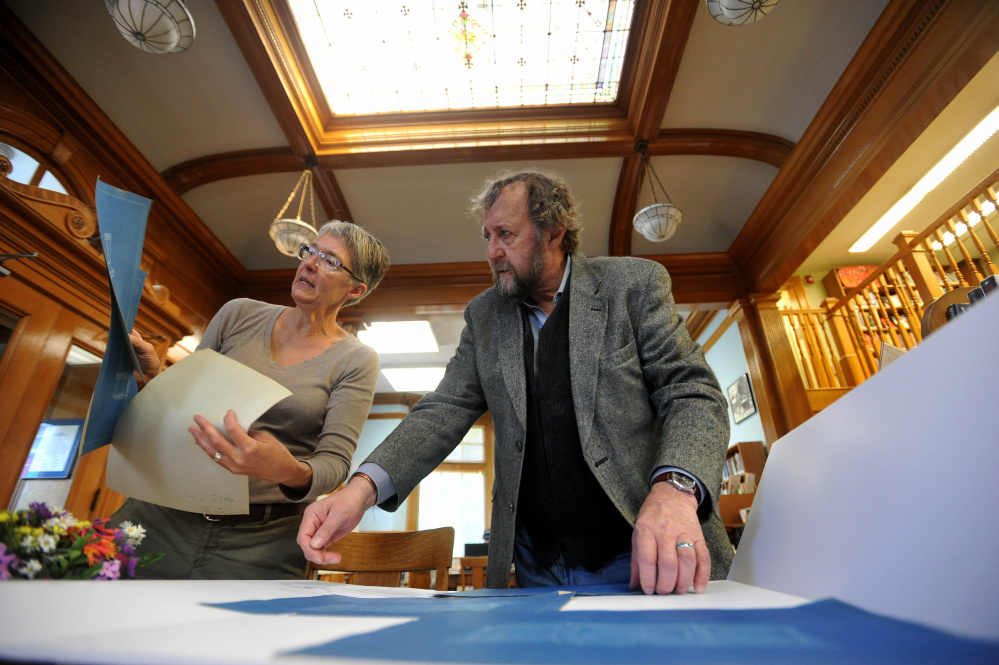 Lynne Hunter, left, adult services librarian, and David Olson, director of the Wilton Library, create a poster displaying architectural renderings of furniture in the Wilton Library on Goodspeed Street in Wilton on Friday. The library is celebrating it’s 100th year Saturday.