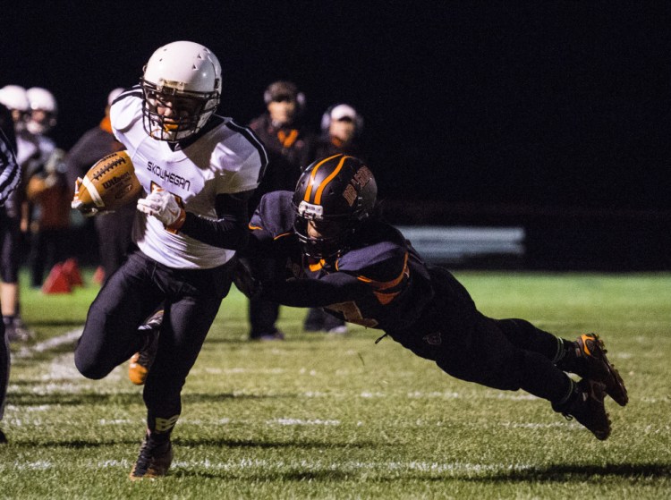 Portland Press Herald photo by Whitney Hayward 
 Skowhegan wide receiver Jon Bell escapes the tackle of Brunswick's Ben Palizay en route to the end zone Friday night in Brunswick.