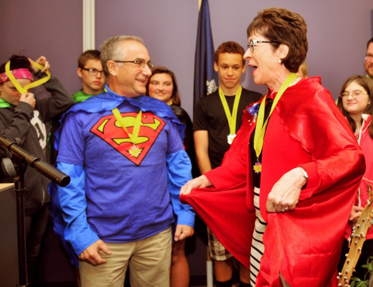 Staff photo by Joe Phelan
Boys and Girls Club of Greater Augusta board member Dr. Roy Miller, left, watches as U.S. Sen. Susan Collins models the cape with a lightning bolt and letter C that he presented her Saturday during an awards ceremony at Kaplan University in Augusta. The capes were part of superhero-themed fundraising running events that the club held in the morning.