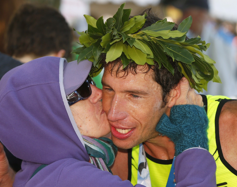 Maine Marathon men’s winner Evan Graves, 34, receives a congratulatory kiss from his mother, Roxie Brechlin, of Bar Harbor at the finish line Sunday in Portland.