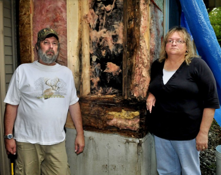 Chris and Janet Weeks stand beside a rotting section of the front of their home Tuesday in Oakland. The Weekses claim the builder of the 14-year-old home failed to prevent rainwater from infiltrating the building wall and causing the sheathing and framing materials to rot.