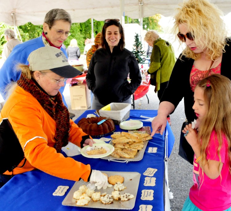 Amelia Berls and her mother, Amy, select desserts from the Beth Israel Synagogue booth on Sunday during the Harvest Fest and Festival at the Falls event in Waterville. Serving is Judy Hansen, left, as  Barbara Jolovitz-Childers and Rabbi Rachel Isaacs watch.