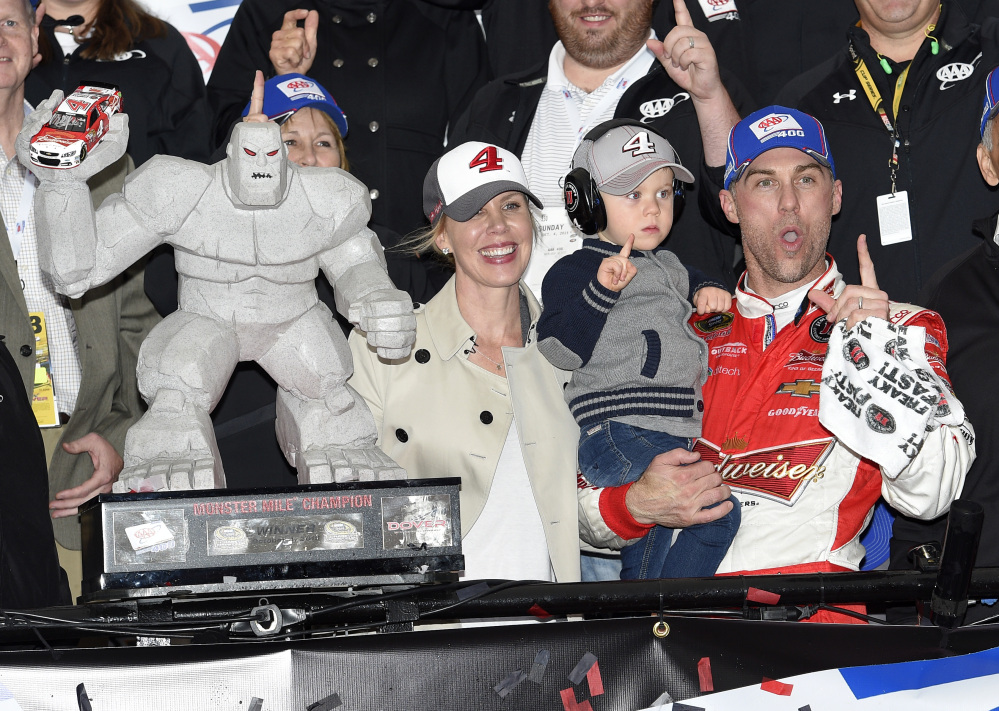 Kevin Harvick, right, celebrates and poses with the trophy in Victory Lane with his son Keelan, second from right, and wife DeLana, left, after he won the NASCAR Sprint Cup race Sundayat Dover International Speedway in Dover, Del.