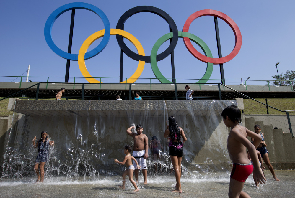 FILE - In this July 28, 2015 file photo, children play in a water fountain next to Olympic rings at Madureira Park in Rio de Janeiro, Brazil.