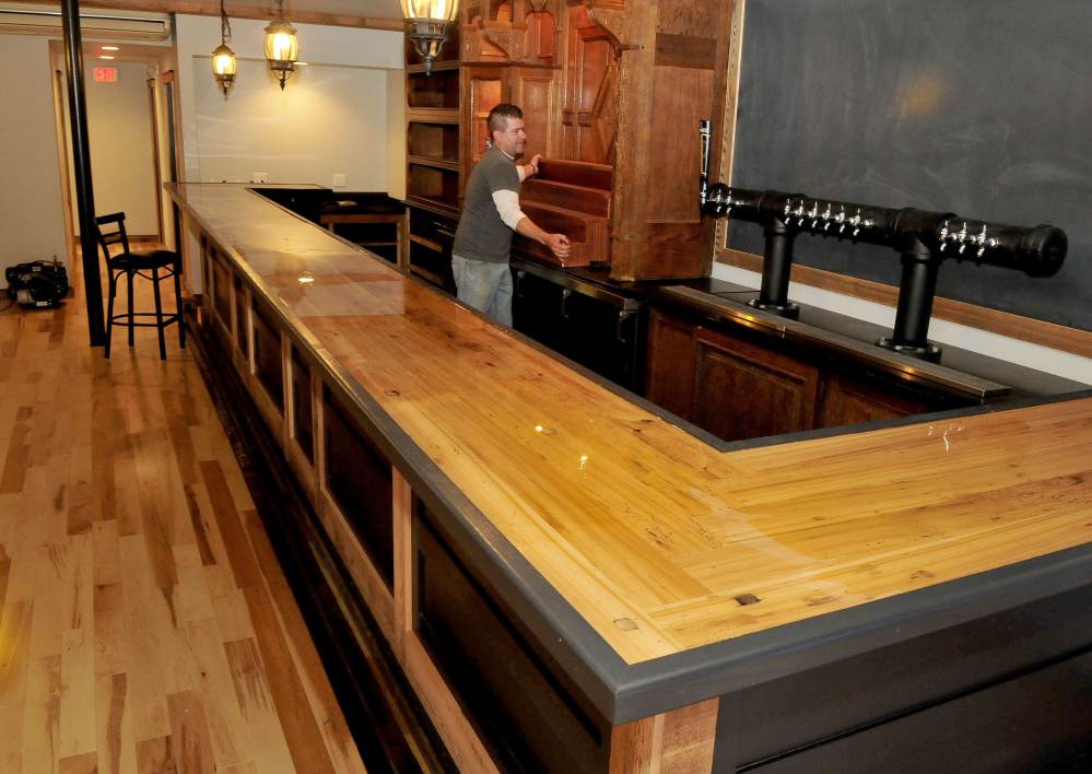 Woodworker Dustin Burphy centers a piece of antique wood cabinetry into the shelves behind the bar at the new Tucks Ale House in Farmington on Monday. Much of the interior is from reclaimed materials.