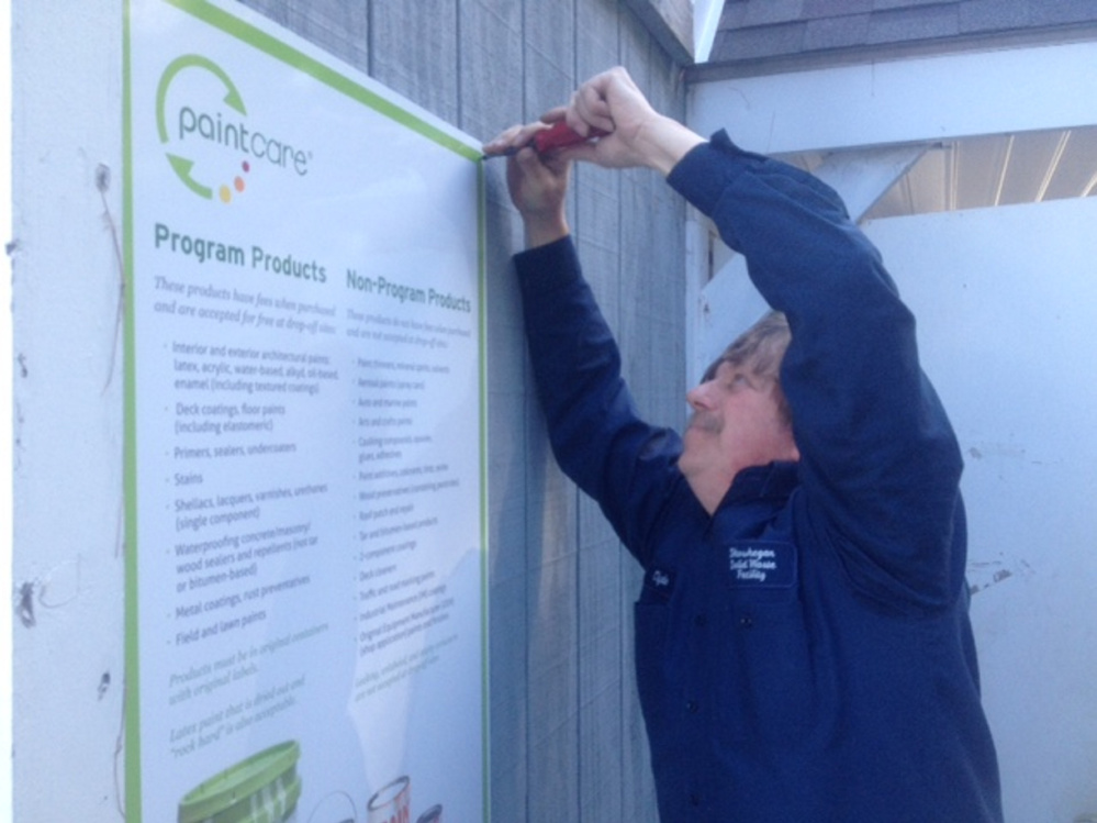 Skowhegan town employee Clyde Merrill puts up signs Thursday at the town’s transfer station announcing the new Paint Care recycling program.