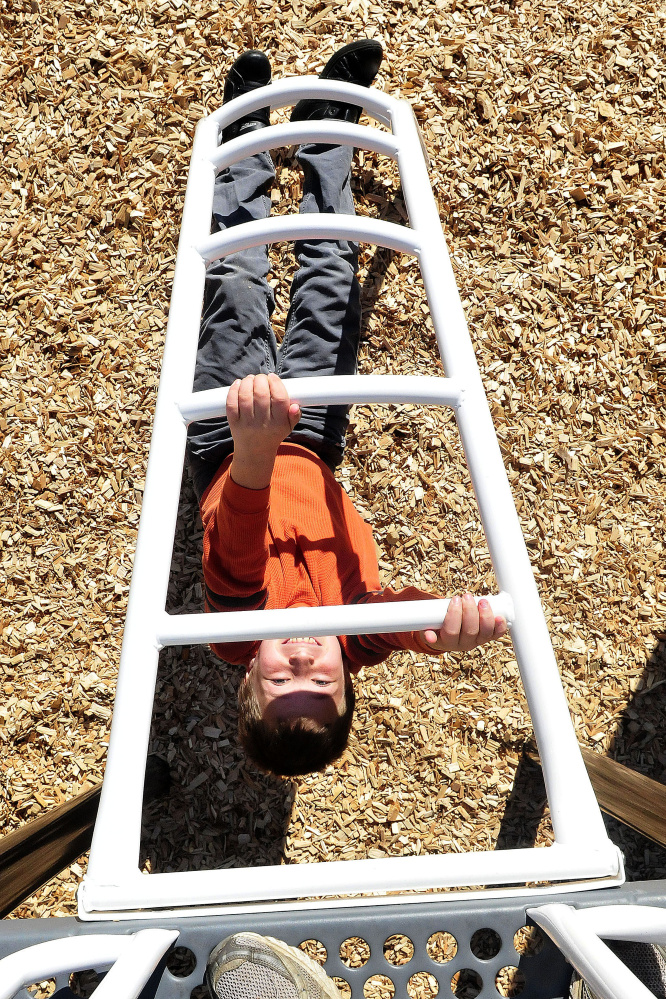 As seen from the top of new playground equipment, Canaan Elementary School student Joshua Rairdon makes his way up underneath a ladder on Thursday.