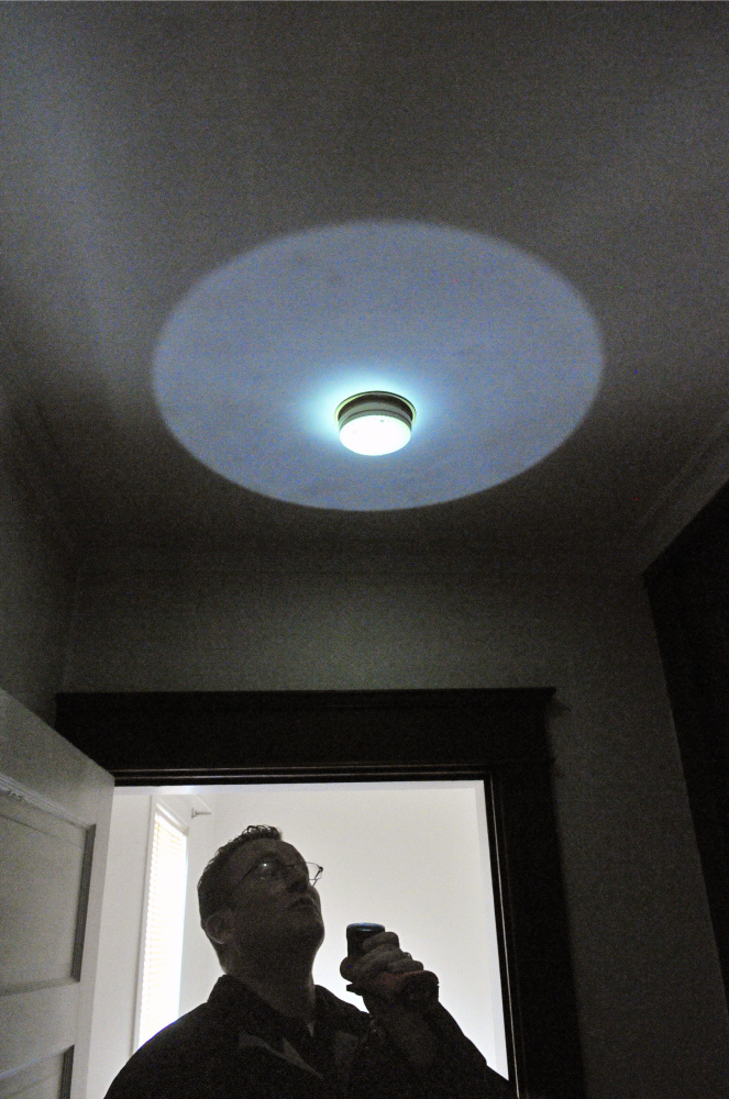 City of Augusta Code Enforcement Officer Robert Overton points a flashlight at a smoke alarm during an Oct. 2 inspection of an apartment building.