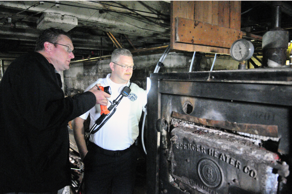 City of Augusta Code Enforcement Officer Robert Overton and Deputy Fire Chief David Groder look at an old heating system during an Oct. 2 inspection of an apartment building.