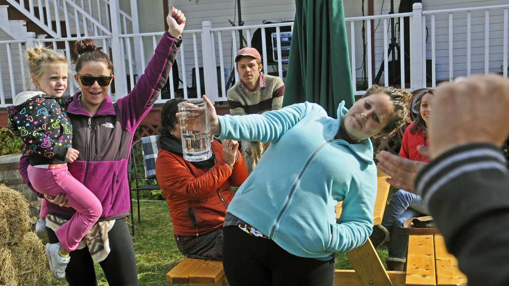 Laila Ring, left, and Kaitlin Sweeney cheer on Laila’s mother, Devhan Ring, as she wins the stein hoisting contest during harvest festivities on Saturday in Belgrade Lakes village.
