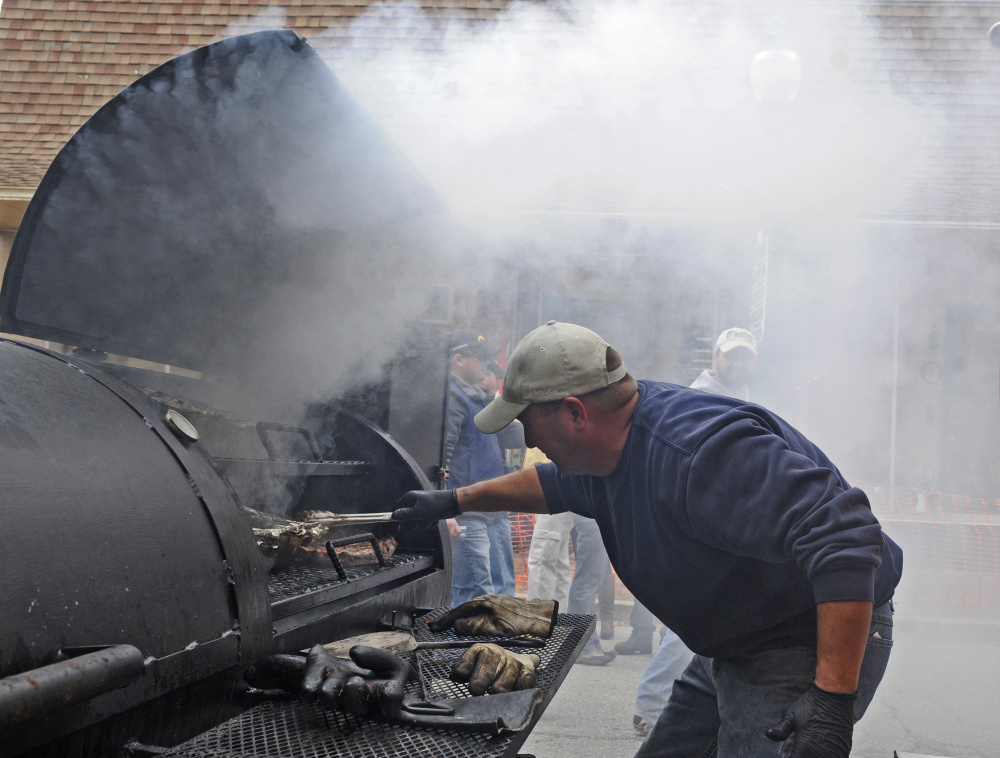 Kris Levasseur tends meat in the smoker at the K and D Barbecue booth during the Swine and Stein festivities on Saturday on Water Street in downtown Gardiner.