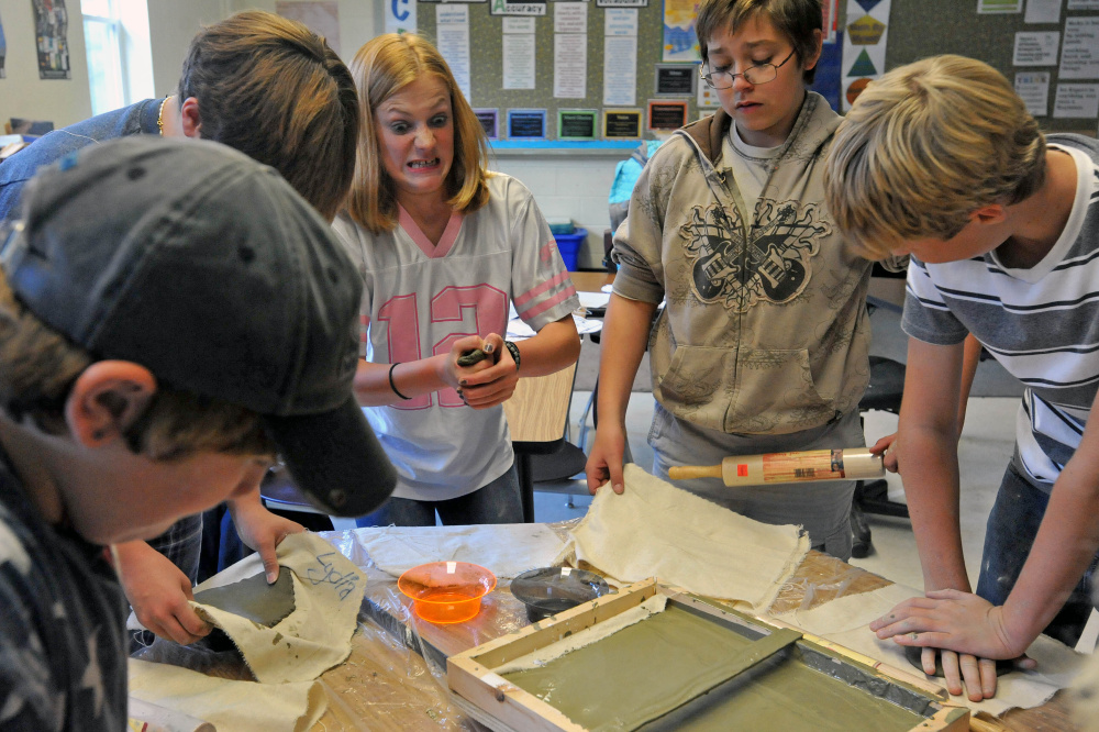 Katie Vanvliet, 13, center, grimaces as she molds a piece of clay during art class at the Cornville Regional Charter School on Wednesday. Every Wednesday for two hours students at the Cornville school get hands-on instruction from two artists and two musicians who visit students in groups.