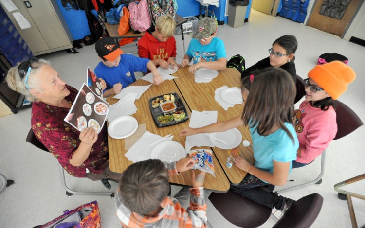 Sally Baker, left, shows examples of edible art to a group of fifth-graders during art class at Cornville Charter School in Cornville on Wednesday. Every Wednesday for two hours students at the Cornville school get hands on instruction from two artists and two musicians who visit students in groups.