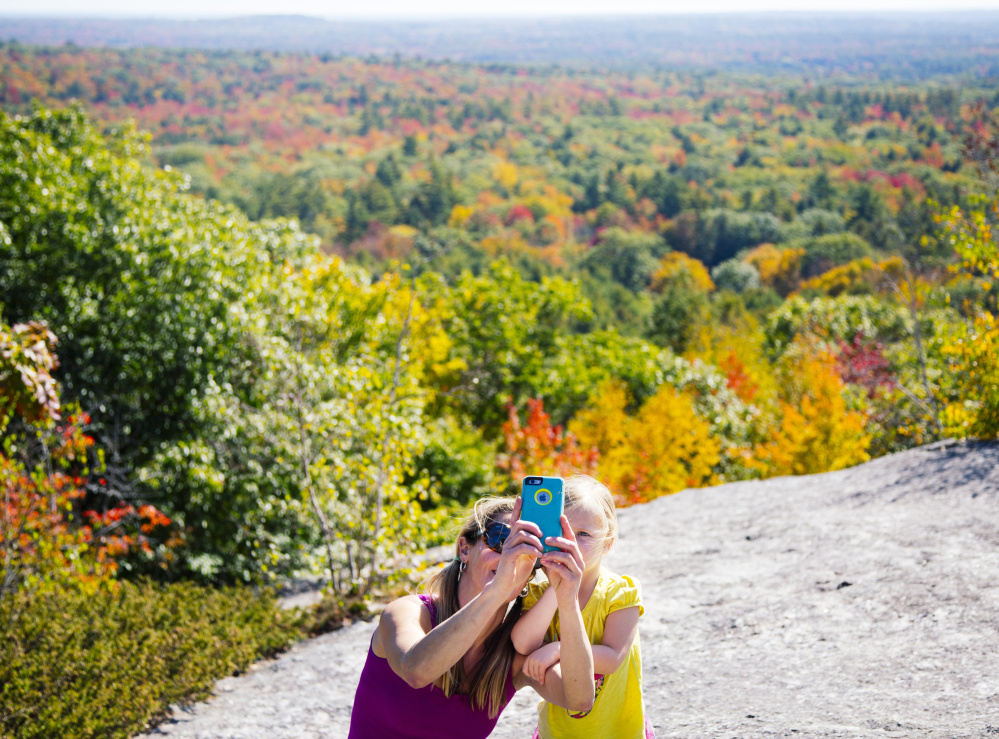 Kristin Brennan, left, takes a selfie with Pearl Brennan, 3 years old, both from the Portland area, at the summit of Bradbury Mountain at Bradbury Mountain State Park in Pownal on Monday.