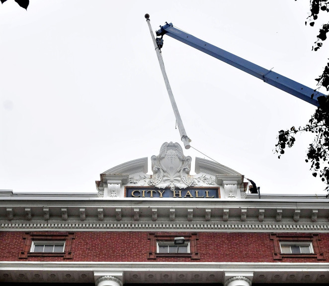 A worker holding a rope guides the Waterville City Hall 100-year-old flagpole away from the roof as a crane operator lowers it to the ground on Tuesday. The workers also removed 4,000 bricks. The work was in anticipation of next year’s roof replacement project.