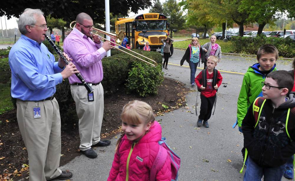Benton Elementary School music teachers David Hoagland, left, and Josh Lund play as students get off the bus for school on Tuesday morning.