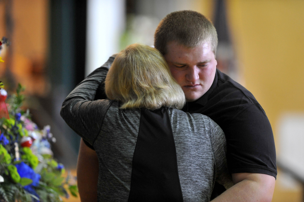 People embrace during a celebration of Michael Holland’s life at the Jay Community Building on Wednesday.