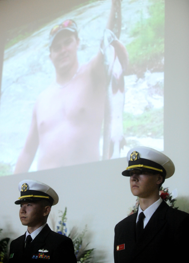 Members of the Coast Guard stand at attention as pictures of Michael Holland are displayed on the wall behind them during a celebration of Michael Holland’s life at the Jay Community Building on Wednesday.