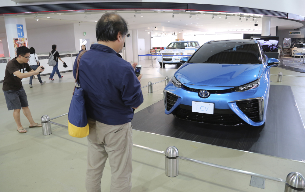 In this June 26, 2014 photo, visitors look at Toyota Motor Corp.’s new fuel cell vehicle (FCV) on display at a Toyota showroom in Tokyo. Toyota, under ambitious environmental targets, is aiming to sell hardly any regular gasoline vehicles by 2050, only hybrids and fuel cells, to radically reduce emissions.