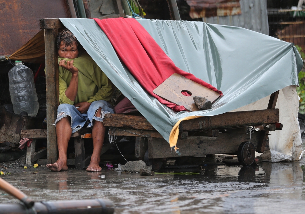 A Filipino man sits inside his makeshift home as strong winds and rains caused by Typhoon Koppu hits the coastal town of Navotas, north of Manila, Philippines on Sunday.