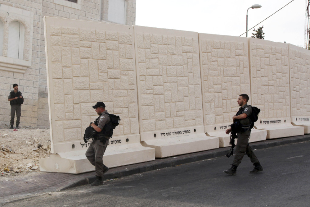 Israeli border policemen walk by the wall being built between Palestinian and Jewish neighborhoods in Jerusalem Sunday.