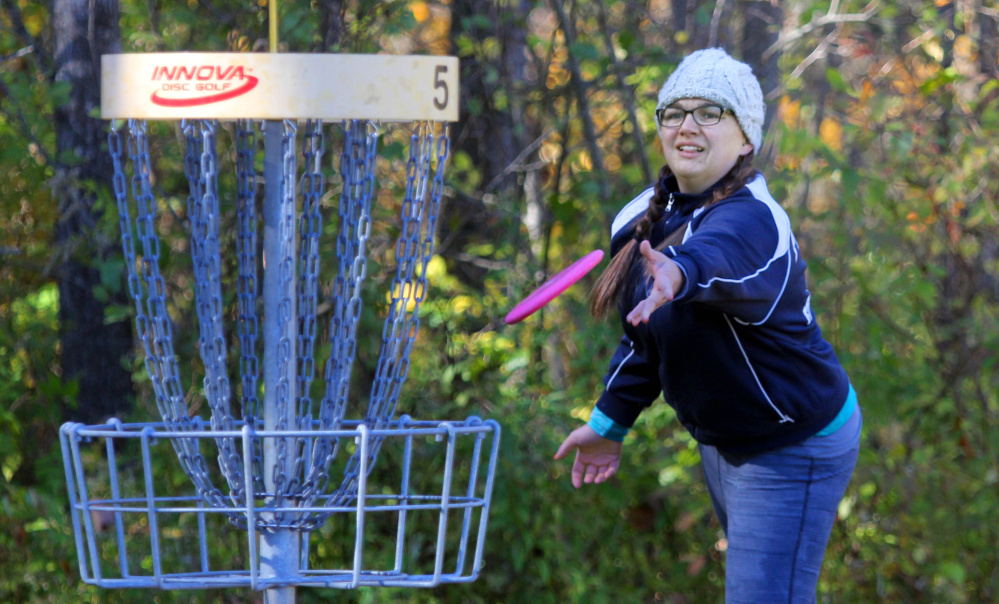 Megan Norton of New Gloucester tosses her disc toward the basket on No. 5 during the 2nd annual Porcupine Ridge PDGA Open at Porcupine Ridge on Sunday in Augusta.