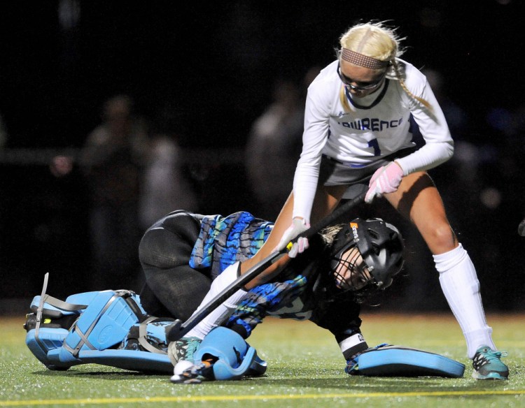 Staff photo by Michael G. Seamans 
 Lawrence junior forward Hallee Parlin (1) tries to get control of the ball from Old Town goalie Corinne Saucier during the second half of a Class B North quarterfinal game Tuesday night at Thomas College.