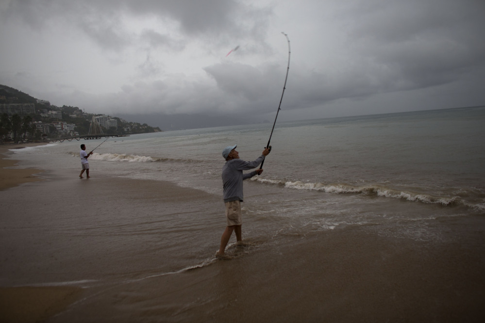 Mike Anderson of Minnesota, right, fishes alongside his friend and local fisherman Miguel Pilas during a steady rain as Hurricane Patricia approaches Puerto Vallarta, Mexico, on Friday