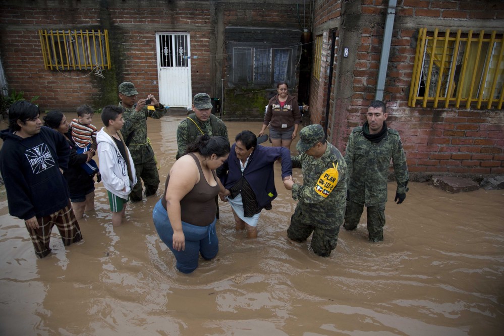 Soldiers help a woman leave her flooded house in in Zoatlan, Nayarit state, about 100 miles northwest of Guadalajara,  Mexico. Hurricane Patricia made landfall Friday on a sparsely populated stretch of Mexico’s Pacific coast as a Category 5 storm but weakened to a tropical storm when it ran into mountains. It dumped torrential rains that authorities warned could cause deadly floods and mudslides. (AP Photo/Eduardo Verdugo)