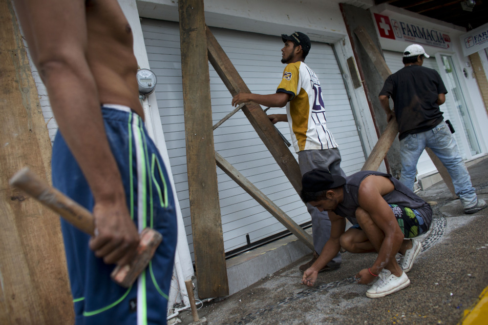 Men remove protective wood beams from the front of a business the morning after Hurricane Patricia passed further south sparing Puerto Vallarta, Mexico, on Saturday.