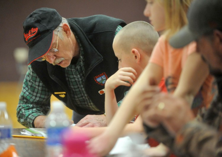 Hal Currier, an outdoor education instructor, helps Nicholas Sweeney, 12, of Cambridge, learn how to use a map and compass during a hunter safety course Wednesday at Harmony Elementary School.