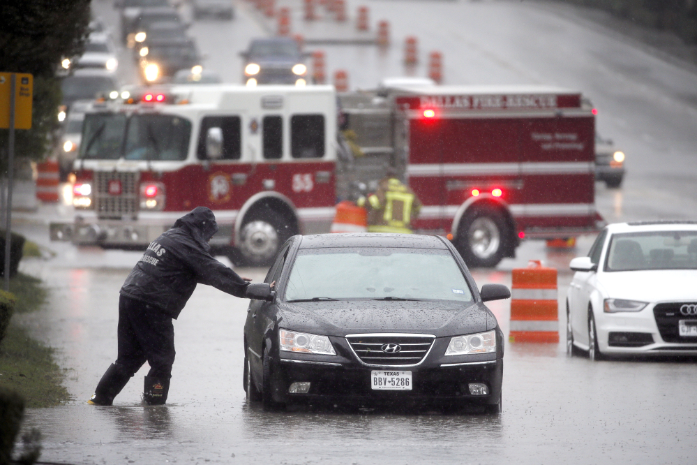 A Dalls Fire Rescue responder makes his way over to a stalled vehicle to check on the driver still inside on Friday in Dallas.