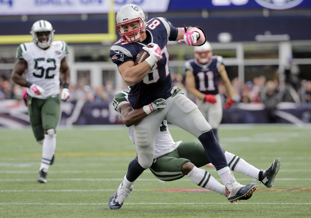 New England Patriots tight end Rob Gronkowski (87) drags New York Jets free safety Marcus Gilchrist (21) as he runs after catching a pass during the second half Sunday in Foxborough, Mass. The Patriots won 30-23.