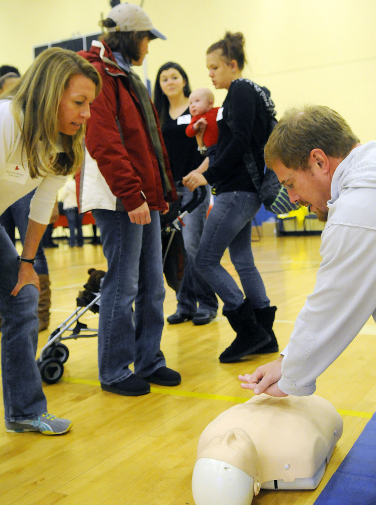 Dov Cohen, of Gardiner, learns about chest compressions Sunday from American Heart Association employee Meredith McNeil, left, during Little Heart Hero Day at the Augusta YMCA. Cohen attended the event with his wife, Missy, second from left, whose daughter, Megan Trussell, holds her infant son, Kasen Trussell, who is afflicted with a heart ailment. At center is Missy Trussell’s niece, Chloe Roy.