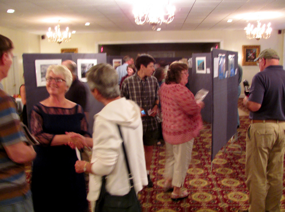 Linda Sikes, chairperson for the Western Mountain Photography Show, and sponsored by the Rangeley Friends of the Arts, is shown in lower left greeting photography enthusiasts at the Awards Reception.