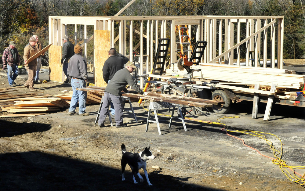 Homeowner Jeff Chadbourne, center, watches as friends and volunteers help build a new barn at his farm in Harmony on Monday after fire destroyed the old barn last week, killing several farm animals.