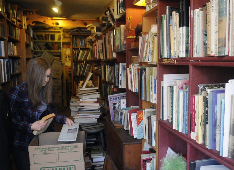 Deni Merrill packs monographs Monday at RiverBooks in Hallowell, which her mother, Edda Briggs Thiele, is closing at the end of the month. The tiny 24-year-old business operated on the honor system, with clients leaving money behind for books they selected.