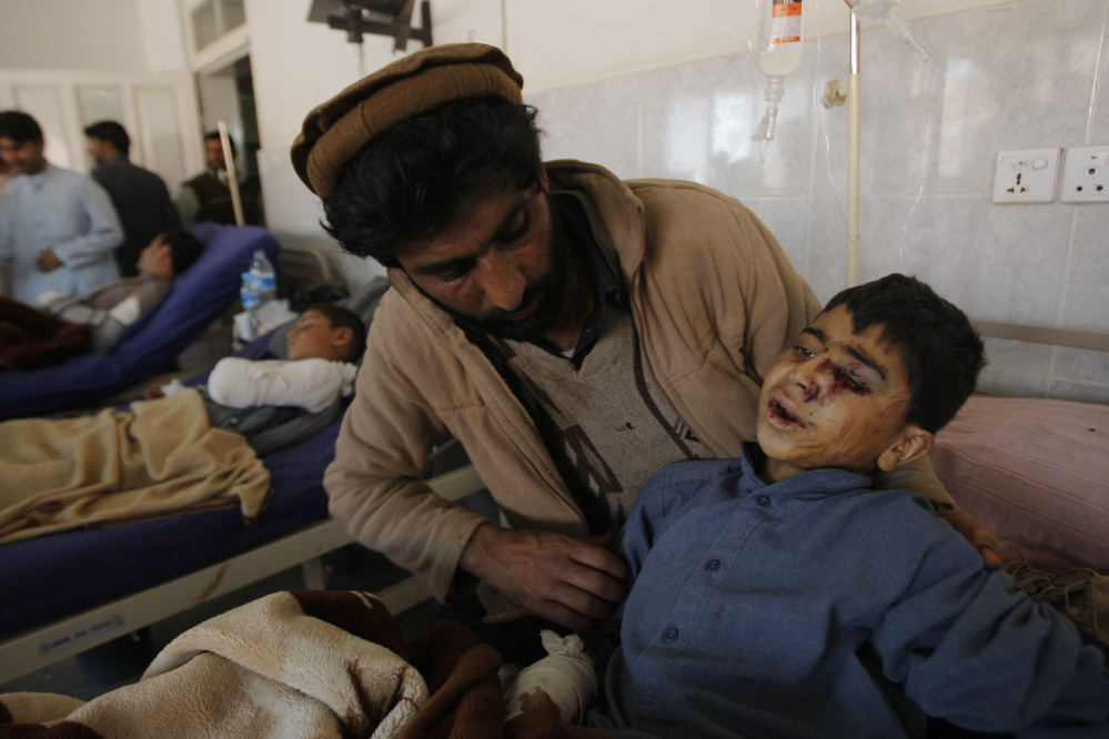 A family member comforts an injured boy at a local hospital in Peshawar, Pakistan, Tuesday, Oct. 27, 2015. Officials say rescuers are struggling to reach quake-stricken regions in Pakistan and Afghanistan. (AP Photo/Mohammad Sajjad)