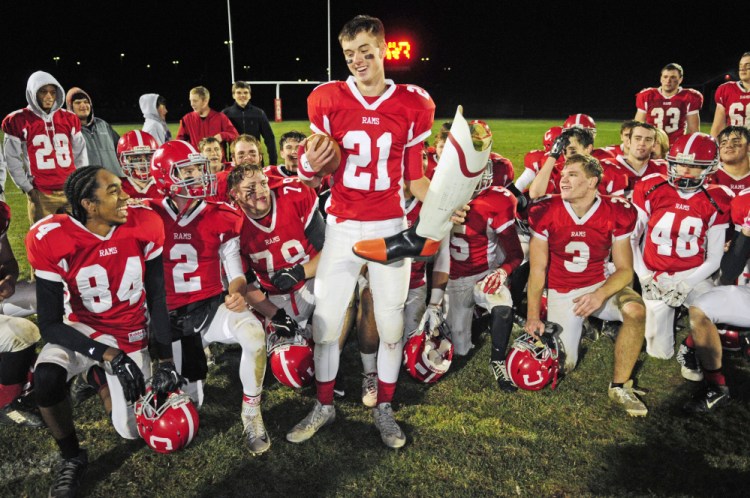 Cony’s Lucas Tyler (21) and teammates celebrate with the boot trophy after defeating Gardiner in the 138th game between the long-time rivals Friday at Alumni Field in Augusta.