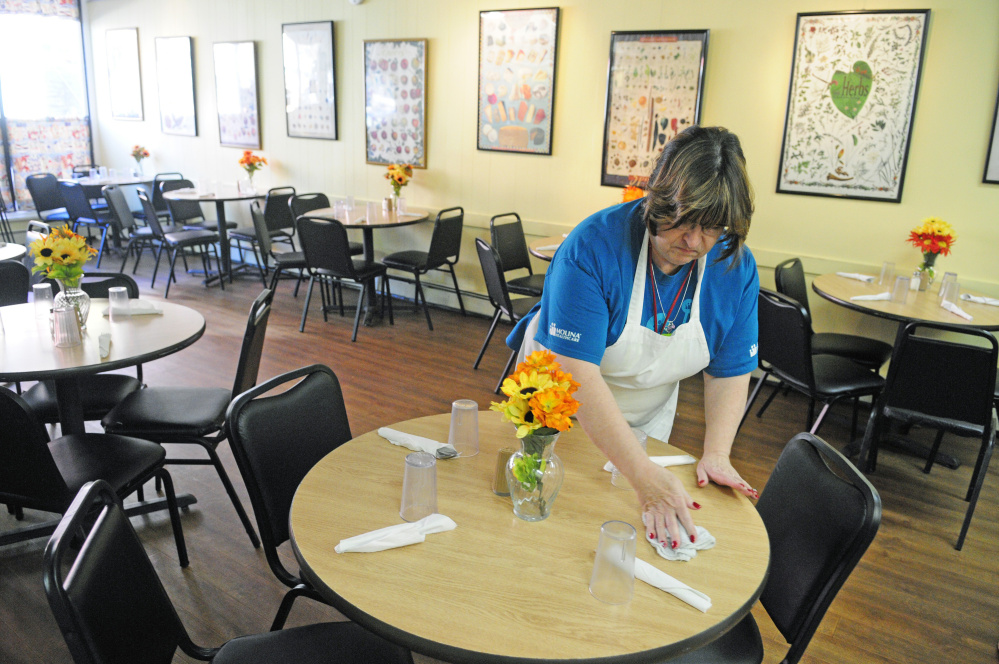 Paula Papsis, one of the volunteers from Molina Healthcare, sets tables before lunch on Friday at Bread of Life Soup Kitchen in Augusta.