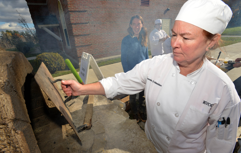 Brenda Madden with the culinary class at Kennebec Valley Community College, checks on her calzone in the wood oven for class at the Alfond campus on Friday.