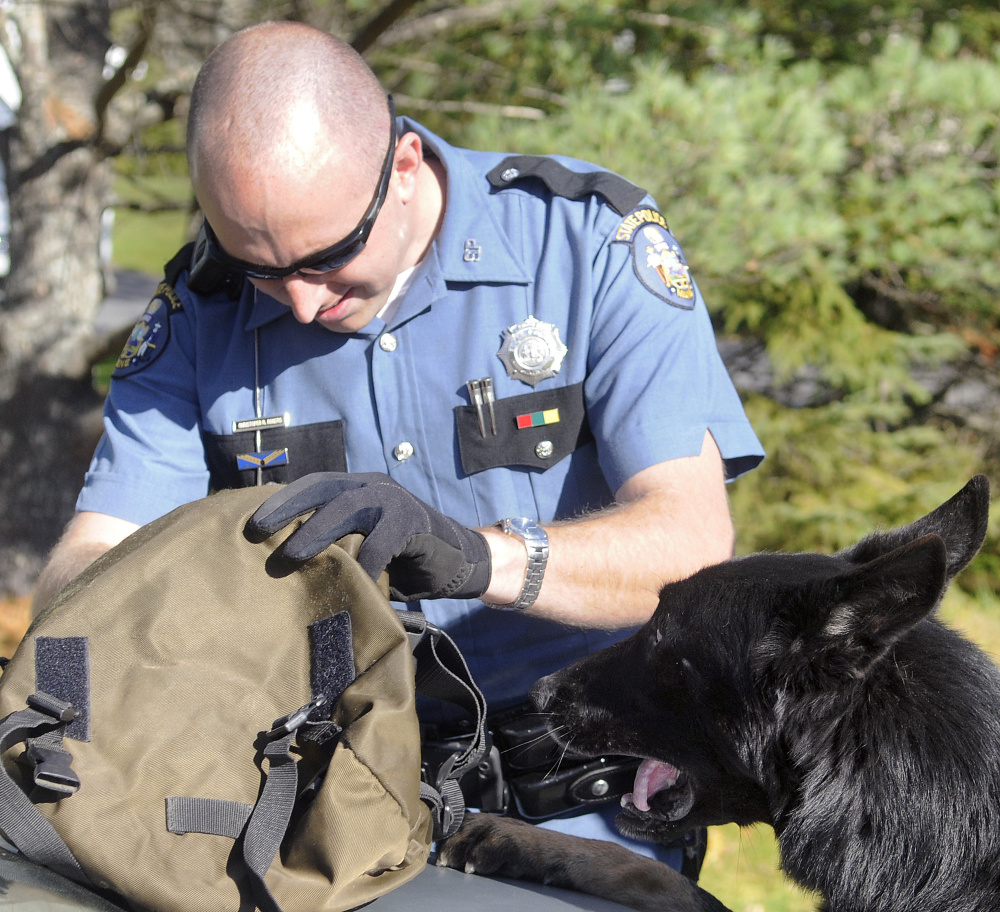 Maine State Police Trooper Chris Rogers searches a satchel as a drug sniffing dog checks out the bag during a traffic stop Friday in Chelsea. Maine State Police, state fire marshal investigators and agents from the Maine Drug Enforcement Agency pulled over the car just before 1 p.m. on Hallowell Road and removed the driver and passengers at gun point.