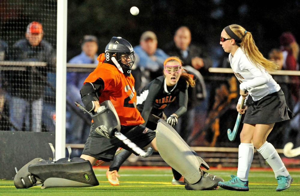 Winslow goalie Delaney Wood watches a shot off the stick of Gardiner’s Amanda Cameron, right, head toward the cage as Winslow’s Susan Grant (8) defends during the Class B North final.