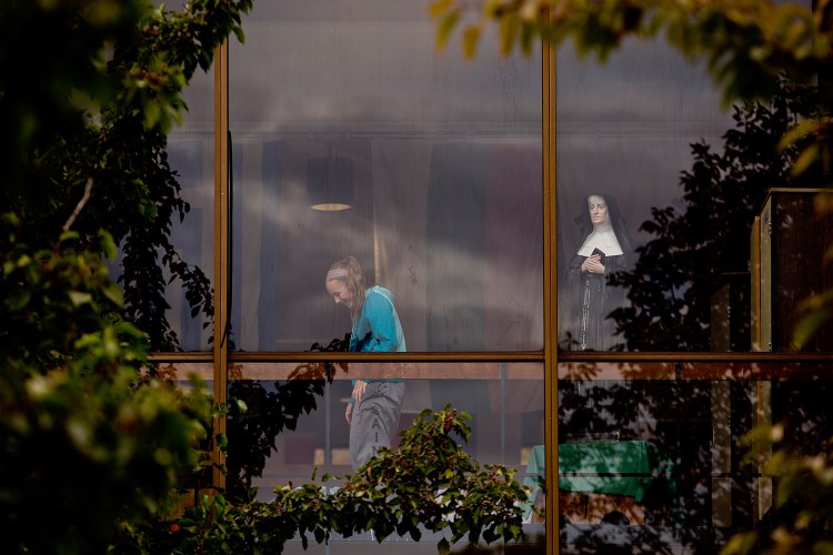 A student at Catherine McAuley High School is seen inside the school with friends Wednesday, next to a statue of Mother Catherine Elizabeth McAuley, an Irish nun who founded the Sisters of Mercy in 1831. The school announced Wednesday it would be ending its relationship with the sisters in 2016. 