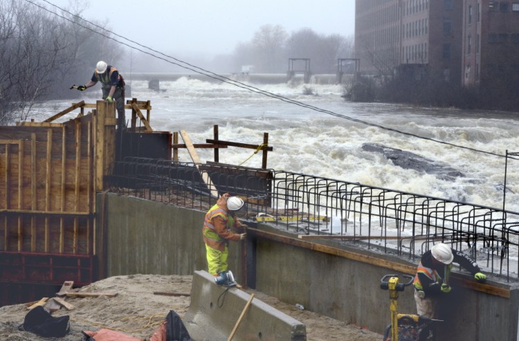 A construction crew works on a bridge alongside the raging Saccarappa Falls on the Presumpscot River in Westbrook after heavy rains in April 2015. 